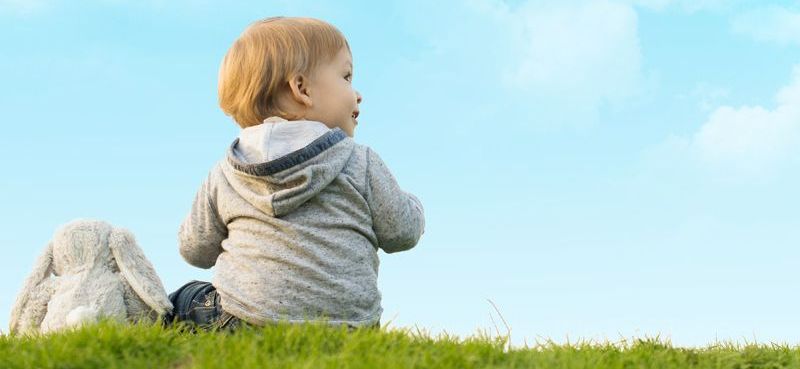 Dziecko z pluszakiem siedzące na trawie